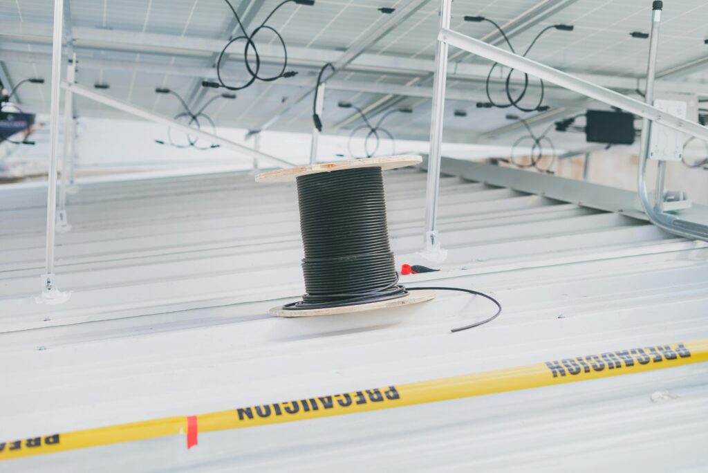 Coiled cable on a rooftop with solar panels, showcasing electrical installation for renewable energy.